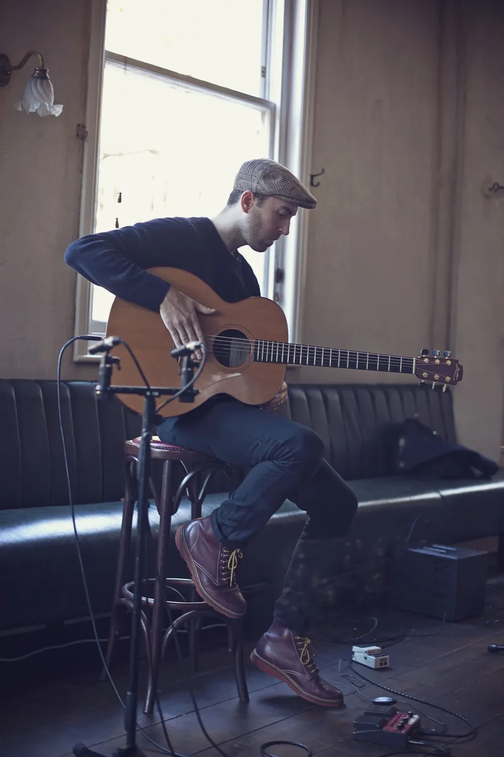 Connor McDonald playing a Lowden acoustic guitar seated by a window